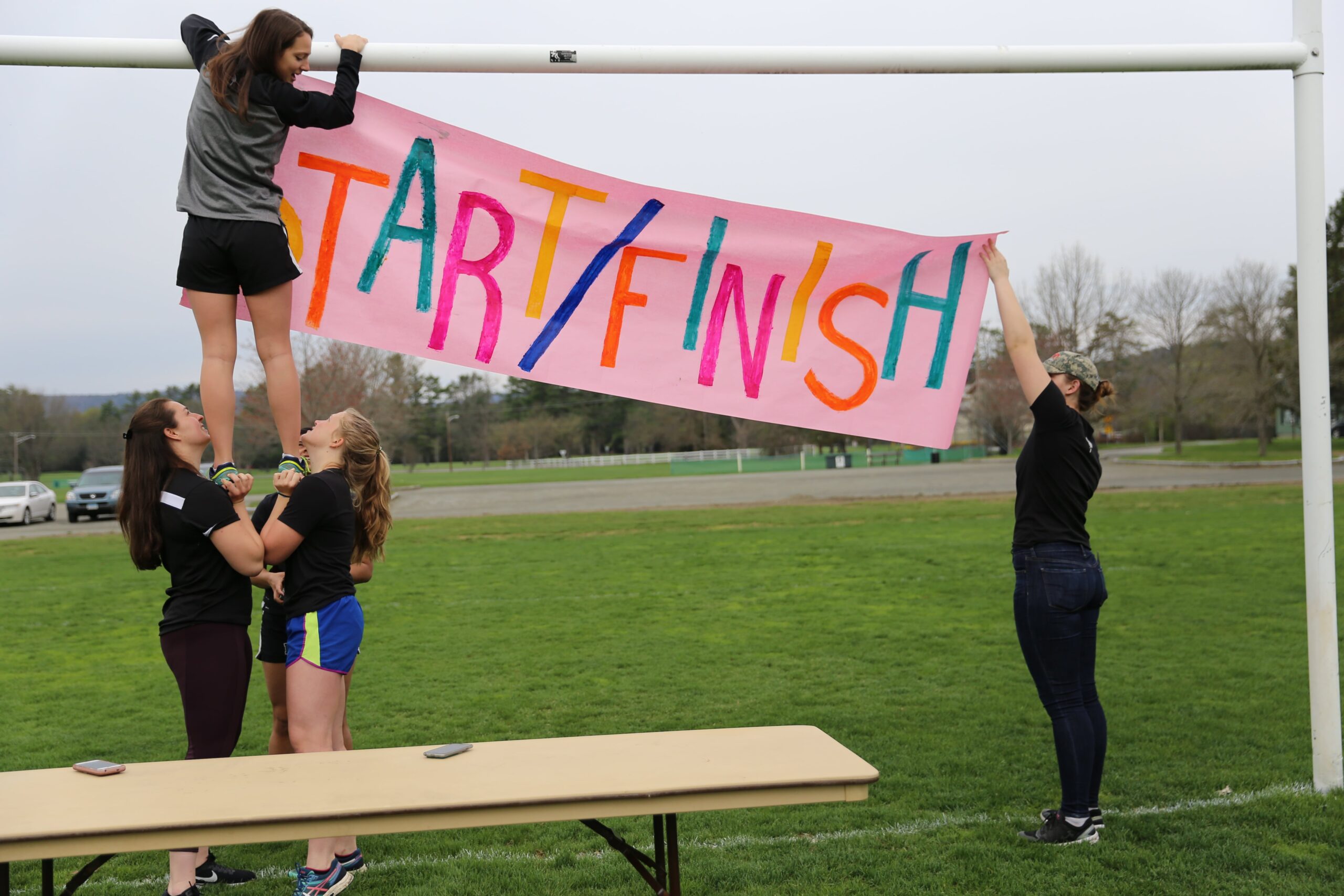 students outdoors setting up a start/finish banner